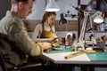 young craftwoman producing a smooth, rounded edge of leather wallet