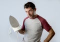 Young crazy desperate and frustrated man doing housework holding iron