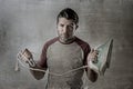 Young crazy desperate and frustrated man doing housework holding iron and cable stressed