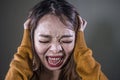 Young crazy desperate and upset Asian Korean woman screaming scared and anxious feeling anger and pain isolated on dark background Royalty Free Stock Photo