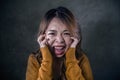 Young crazy desperate and upset Asian Korean woman screaming scared and anxious feeling anger and pain isolated on dark background