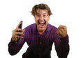 Young crazy happy and excited man celebrating success making money online gambling with mobile phone winning internet bet isolated Royalty Free Stock Photo