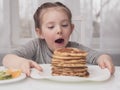 Young crazy little girl eating a stack of pancakes