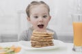 Young crazy little girl eating a stack of pancakes