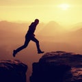 Young crazy man jump on mountain peak. Silhouette of jumping man