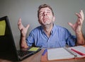 Young crazy stressed and overwhelmed man working messy crying desperate with laptop computer feeling exhausted and frustrated in b Royalty Free Stock Photo