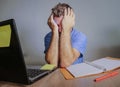 Young crazy stressed and overwhelmed man working messy at office desk desperate with laptop computer covering face with hands frus Royalty Free Stock Photo