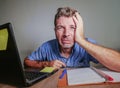 Young crazy stressed and overwhelmed man working messy at office desk desperate with laptop computer crying frustrated and depres