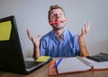 Young crazy stressed and overwhelmed man working messy at office desk desperate with laptop computer feeling exhausted and frustra Royalty Free Stock Photo