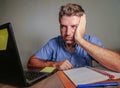 Young crazy stressed and overwhelmed man working messy at office desk desperate with laptop computer feeling exhausted and frustra