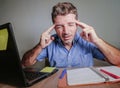 Young crazy stressed and overwhelmed man working messy at office desk desperate with laptop computer suffering headache and depres Royalty Free Stock Photo