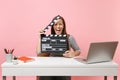 Young crazy woman screaming holding classic black film making clapperboard and working on project while sit at office Royalty Free Stock Photo