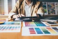 Young creative Graphic designer using graphics tablet to choosing Color swatch samples chart for selection coloring with work too Royalty Free Stock Photo