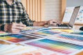 Young creative Graphic designer using graphics tablet to choosing Color swatch samples chart for selection coloring with work too Royalty Free Stock Photo