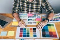 Young creative Graphic designer using graphics tablet to choosing Color swatch samples chart for selection coloring with work Royalty Free Stock Photo