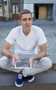 Creative man sitting on sidewalk and using tablet computer Royalty Free Stock Photo