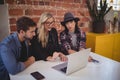 Young creative team using laptop while sitting at coffee shop Royalty Free Stock Photo