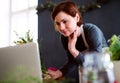 Young creative woman in a flower shop, using laptop. A startup of florist business. Royalty Free Stock Photo