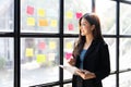 Young creative woman professional using sticky notes in glass wall to writing strategy business plan to development grow Royalty Free Stock Photo