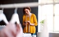 Young creative woman in a studio, using smartphone. A startup of tailoring business. Royalty Free Stock Photo