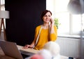 Young creative woman in a studio, using smartphone. A startup of tailoring business. Royalty Free Stock Photo