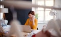 Young creative woman in a studio, using smartphone. A startup of tailoring business. Royalty Free Stock Photo