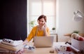 Young creative woman in a studio, using smartphone. A startup of tailoring business. Royalty Free Stock Photo