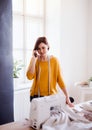 Young creative woman in a studio, using smartphone. A startup of tailoring business. Royalty Free Stock Photo