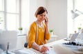 Young creative woman in a studio, using smartphone. A startup of tailoring business. Royalty Free Stock Photo