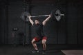 Young crossfit athlete lifting barbell overhead at gym. Man practicing functional training powerlifting workout exercises Royalty Free Stock Photo