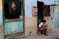 Young Cuban man sitting on a stool eating lunch on the sidewalk