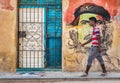 Young cuban walks by a Che Guevara portrait in Old Havana