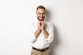 Young cunning businessman steeple fingers and smiling devious, scheming plan, standing over white background