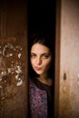 A young curious girl looks out from behind the door of her house. She thinks about going outside. agoraphobia concept Royalty Free Stock Photo