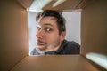 Young curious and suspicious man is looking inside cardboard box. Royalty Free Stock Photo