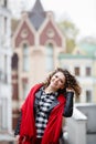 Young curled girl weared in black leather jacket and red scarf on background of old City