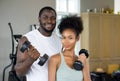 Young curly black hair couple enjoy holiday together in fitness center.  Both lifting barbell with one hand Royalty Free Stock Photo
