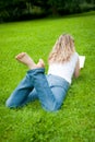 Young curly blond woman reading a book in a park