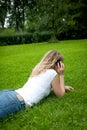 Young curly blond woman telephoning in a park