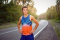 Young curly blonde Caucasian man standing on asphalt forest road looking at camera before jogging Royalty Free Stock Photo