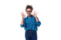 young curly european woman dressed casually in a blue plaid shirt shows a gesture of ok