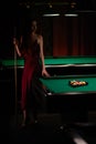 Young curly girl posed near billiard table. Sexy model at red dress. Royalty Free Stock Photo