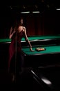 Young curly girl posed near billiard table. Sexy model at red dress. Royalty Free Stock Photo