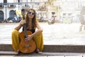 Young curly girl in rounded blue retro hippie sunglasses sitting outdoors