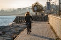 Young curly girl in a yellow hat rides a bicycle at sunset on the promenade road of Maresme, Catalonia, Spain Royalty Free Stock Photo