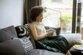 Young curly hair african woman relaxing at home and using mobile phone Royalty Free Stock Photo