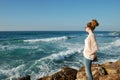 Young curly-haired girl, looking into the distance of the sea, in jeans, glasses Royalty Free Stock Photo