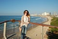 Young curly-haired girl, on the pavement by the blue sea, looking into the distance of the sea, in jeans Royalty Free Stock Photo