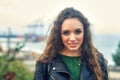 Young curly haired woman in fashionable leather jacket