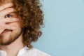 Young curly man with ginger hair smiling and covering his face Royalty Free Stock Photo